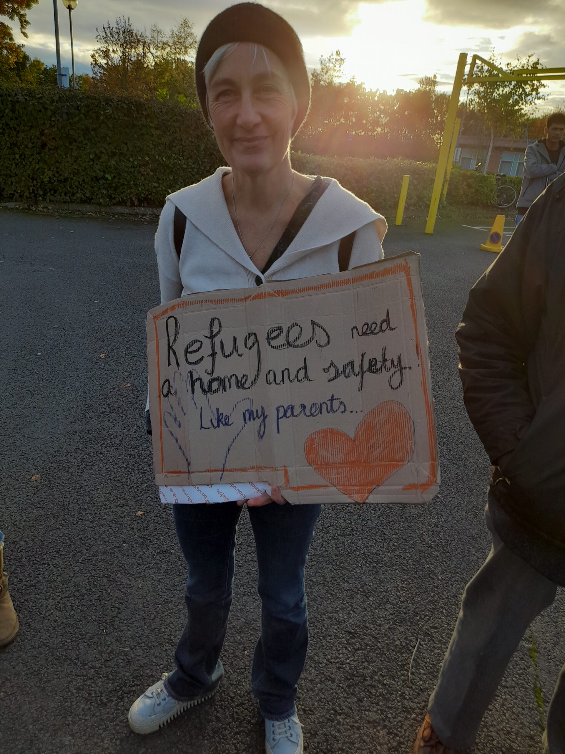 Placard reads "Refugees need a home and safety. Like my parents..."