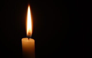 Single candle flame on horizontal black background